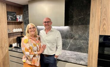 A couple smiling in front of their new kitchen.